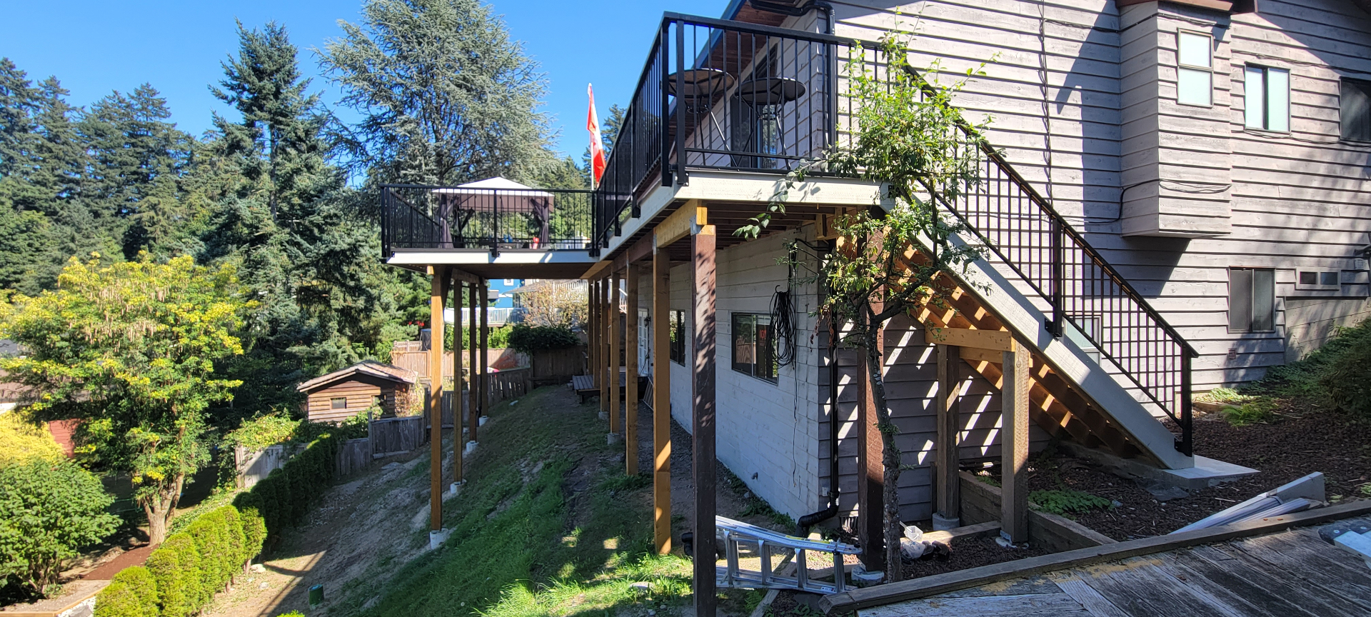 Completed elevated cedar deck with black railing and pergola
