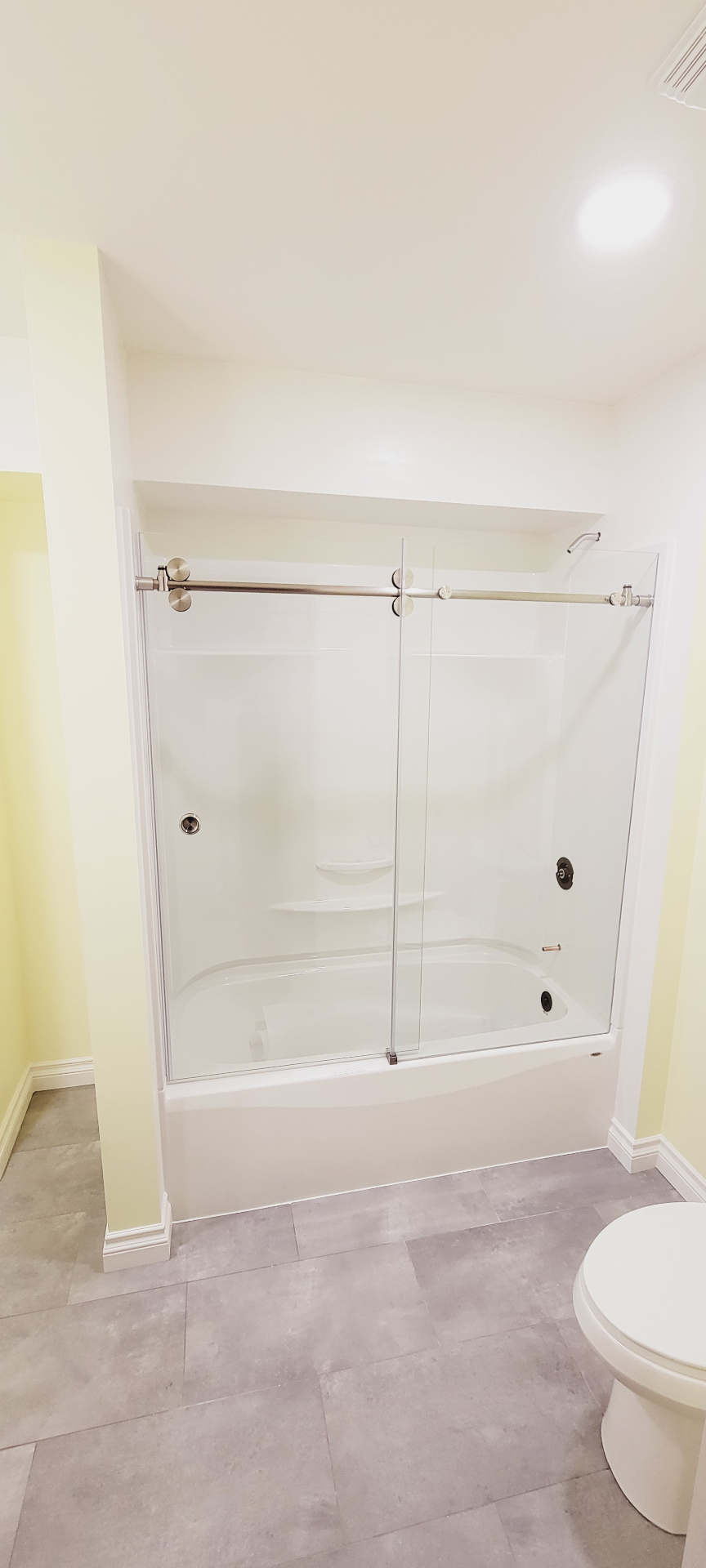 Tub and shower combo with frameless sliding glass door and new tile floor