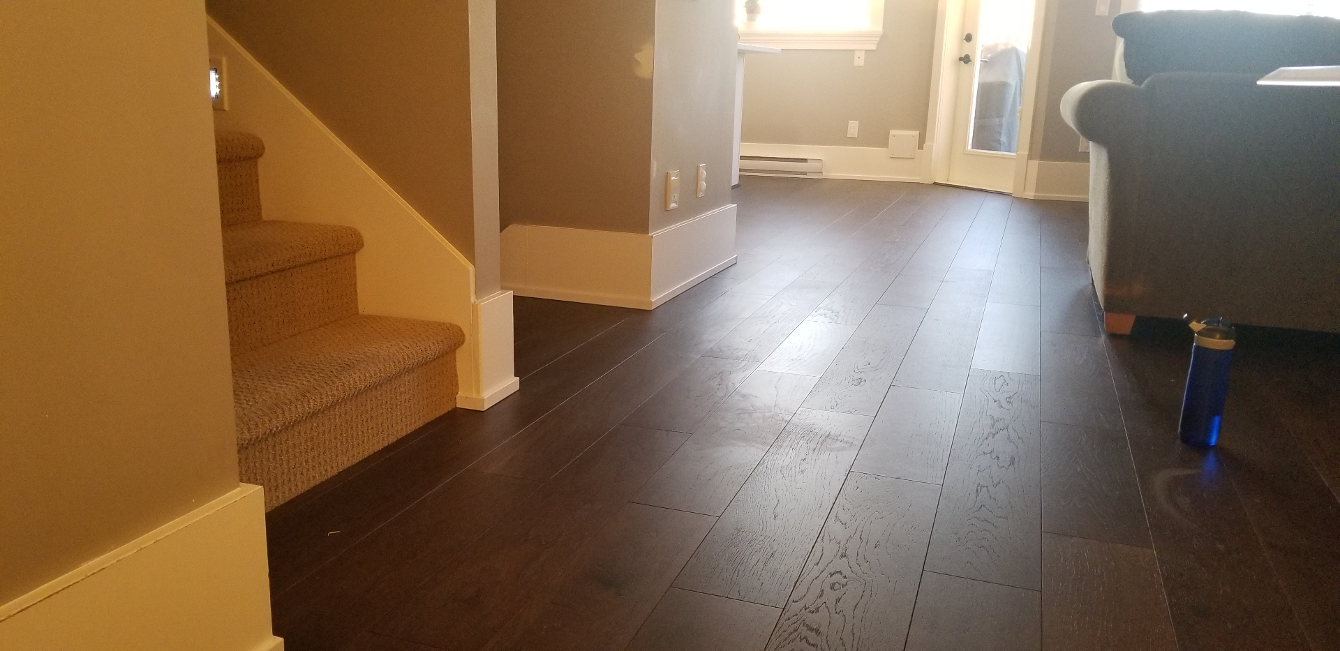 Open living area with new dark hardwood flooring and carpeted stairs