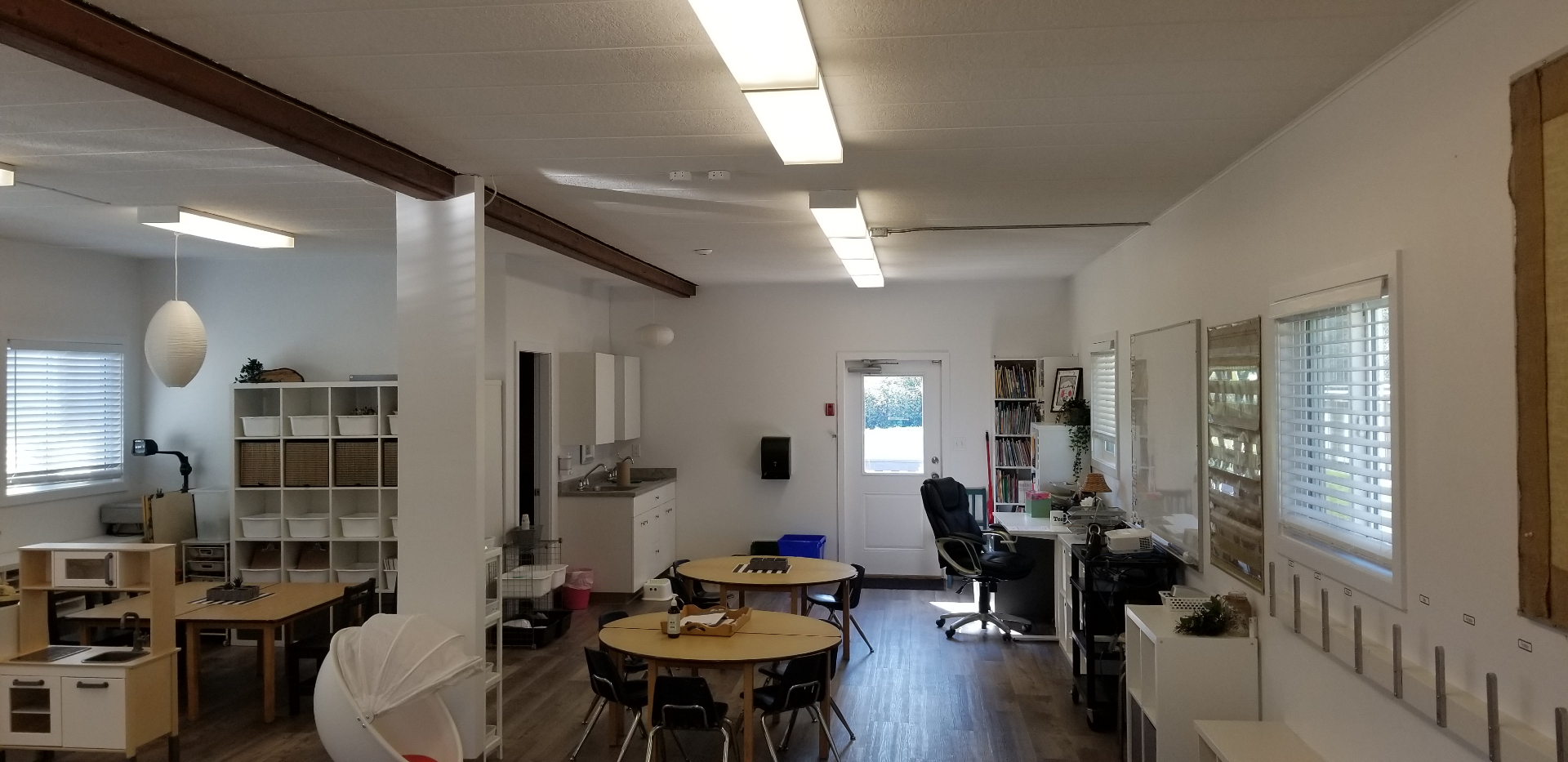 Finished classroom showing kitchenette, work tables, and natural light